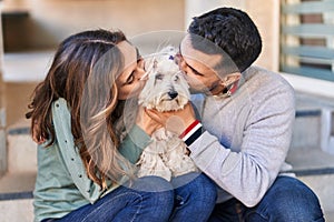 Man and woman kissing dog standing together at street