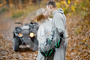 Man and woman kissing near a quad bike in autumn forest