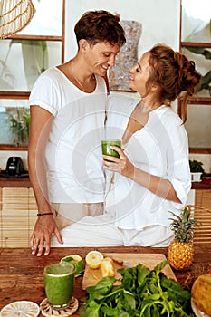 Man And Woman At Kitchen. Romantic Couple Standing Together With Glass Of Detox Cocktail In Hand.