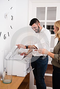 Man and woman laughing over a photo copier