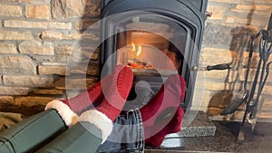 Man and woman lie near a hot burning fireplace, legs stretched out in red socks to the fire, concept of winter relaxation