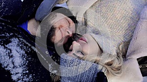 A man and a woman lie in the snow. Lovers lie close to each other in the snow in a winter park. Slow motion.