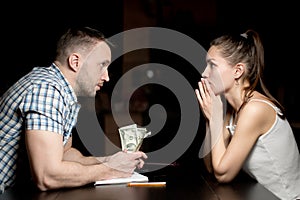 Man and woman look at each other late at night, a man holding savings in dollars