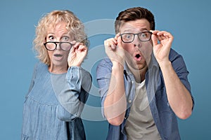 Man and woman look with widely opened mouth into camera in full disbelief.