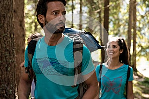 Man and woman looking around while walking along hiking trail path in forest woods.Group of friends people summer