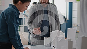 Man and woman looking at blueprints plan on paper to design building model and maquette