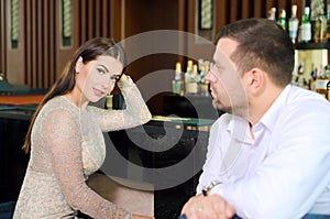 Man and woman are looking at each other. the girl and the guy are sitting in bar, restaurant