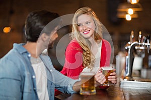 Man and woman looking at each other with holding beer glasses