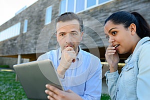 man and woman looking at tablet stood outside property