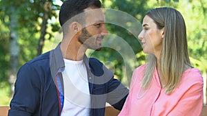 Man and woman in love admiring each other sitting on bench in park, romance