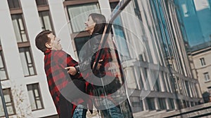 Man and woman in love hug and kiss outside modern buildings in city