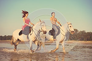 Man and a woman in love with the sea on horseback