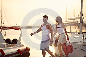 Man and woman in love walking on the dock going on yacht at vacation