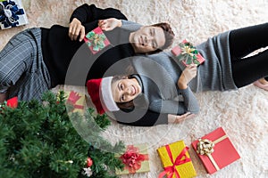 Man and woman lying on carpet on the floor in Christmas decorated room with Christmas tree and box