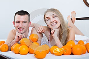 Man and woman lying with orange fruits