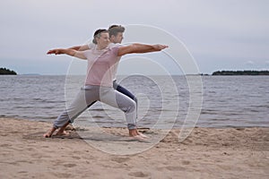 Man and woman making warrior pose on beach