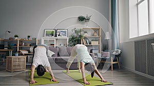 Man and woman married couple doing yoga in apartment on mats together