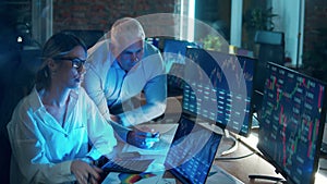 A man and a woman are monitoring stock data on the computers. Teamwork concept.