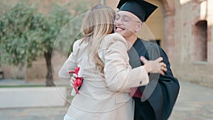 Man and woman mother and son hugging each other celebrating graduation at university