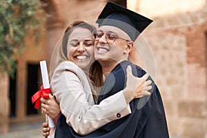 Man and woman mother and son hugging each other celebrating graduation at university