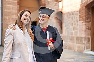 Man and woman mother and son hugging each other celebrating graduation at university