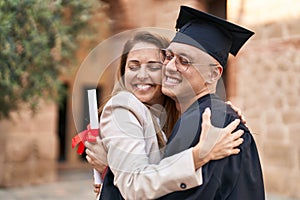 Man and woman mother and son hugging each other celebrating graduation at university