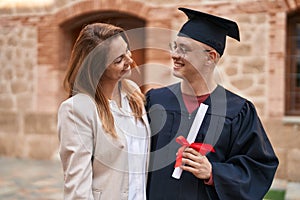 Man and woman mother and son hugging each other celebrating graduation at university