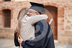 Man and woman mother and son hugging each other celebrating graduation at university
