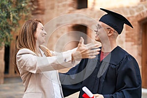 Man and woman mother and son hugging each other celebrating graduation at university