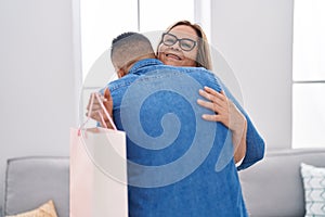 Man and woman mother and son hugging each other holding shopping bag at home