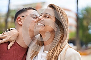 Man and woman mother and son hugging each other and kissing at park