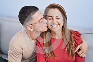 Man and woman mother and son hugging each other and kissing sitting on sofa at home