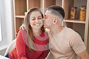 Man and woman mother and son hugging each other and kissing sitting on table at home