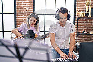 Man and woman musicians playing piano and spanish guitar at music studio