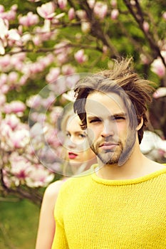 Man and woman on natural background, garden with magnolia flower