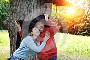 Man and the woman near an oak hide from a rain in the summer day