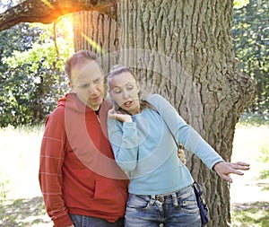Man and woman near an oak in summer day something was seen aside and looked scaredly and with astonishment