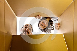 Man and woman opening a carton box and looking inside, surprised and curious.