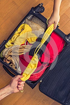 A man and a woman packing a suitcase or luggage for travel. Concept