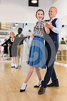 Man and woman performing ballroom dance in dancing room