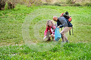 A man and a woman are picking up trash in a field.
