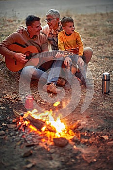 Man and woman on picnic with boy playing guitar
