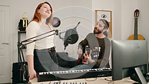 Man and woman playing guitar singing song at music studio