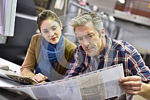 Man and woman in printing house checking print quality