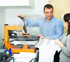 Man and woman printing t-shirt in a workshop