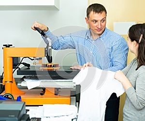 Man and woman printing t-shirt in a workshop