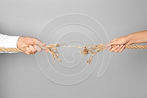 Man and woman pulling frayed rope at breaking point