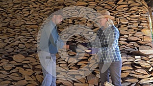 A man and a woman put together firewood in the woodshed helping each other