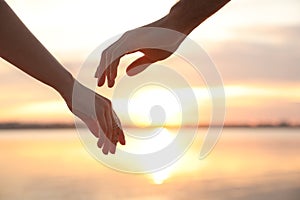 Man and woman reaching hands to each other at sunset, closeup. Nature healing power