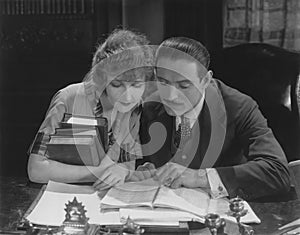 Man and woman reading book at desk